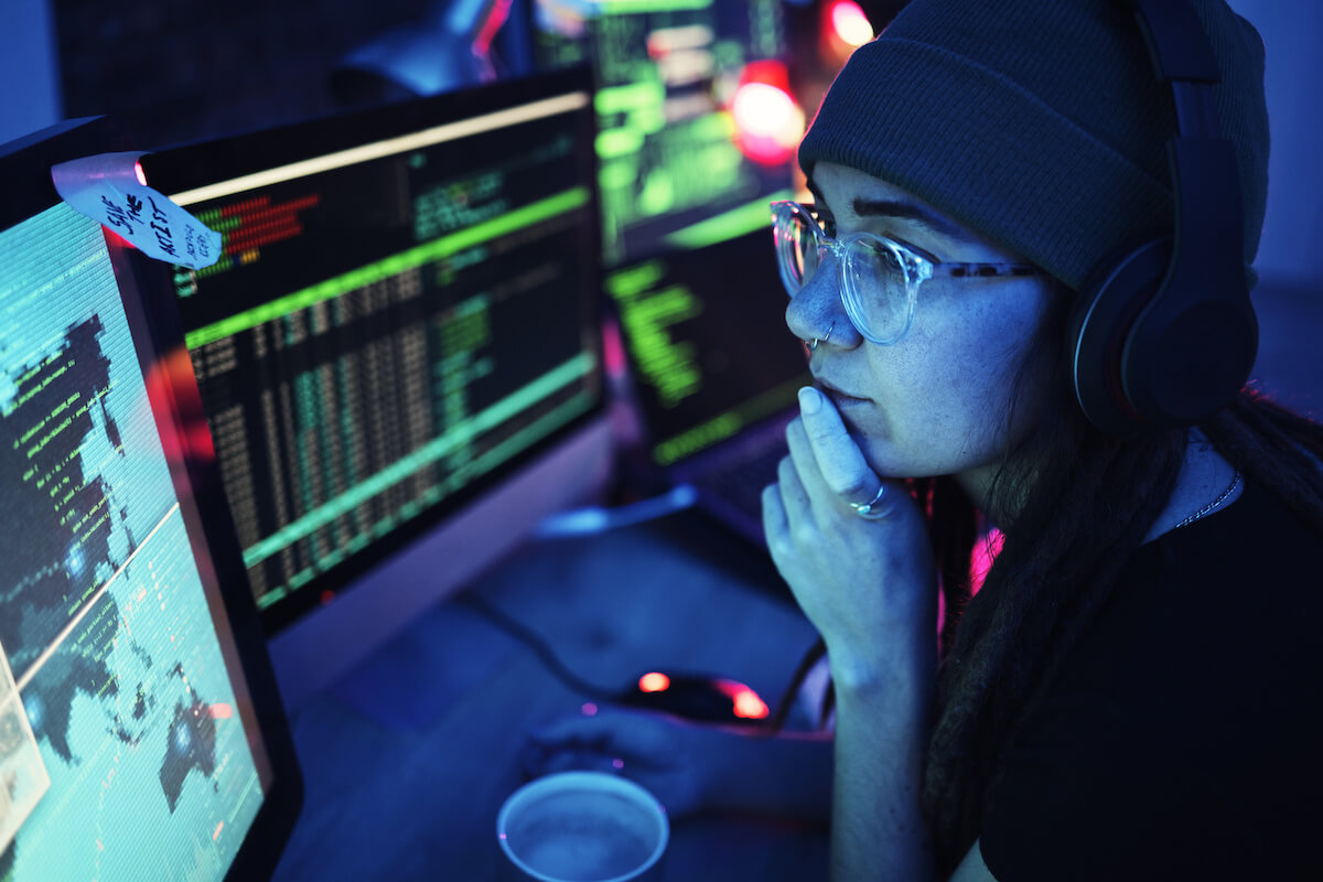 A women working on a computer with two screens at a local cybersecurity event