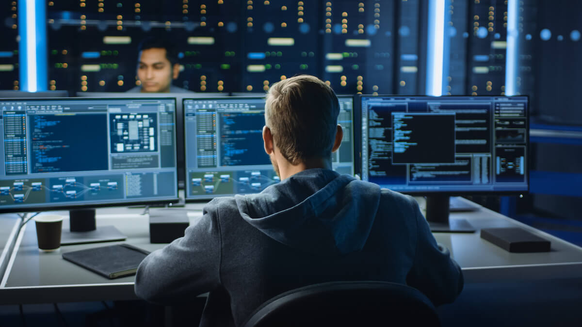 A person working on a computer with multiple screens